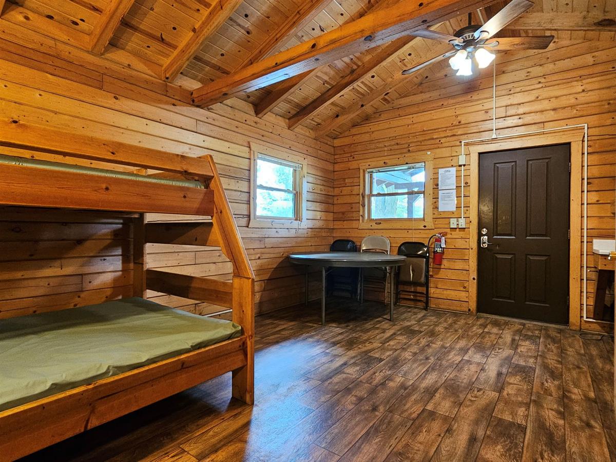 Whitetail - Cabin interior with wood siding, vinyl plank flooring, folding table & bunkbeds.