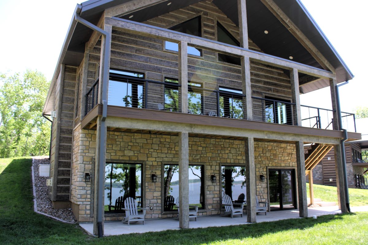 Upper level deck and lower level patio with chairs and picnic table on a modern style cabin, a grill