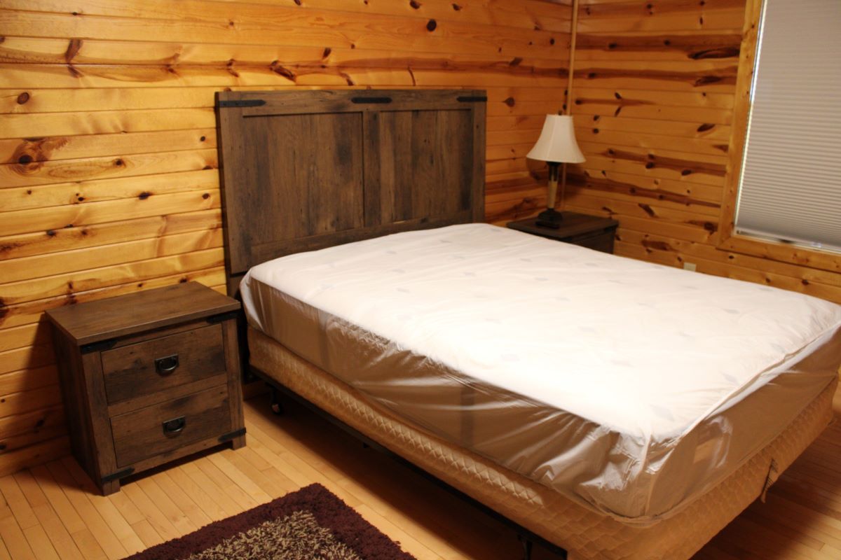 Queen bedroom with bed and side tables with a lamp in a log style cabin