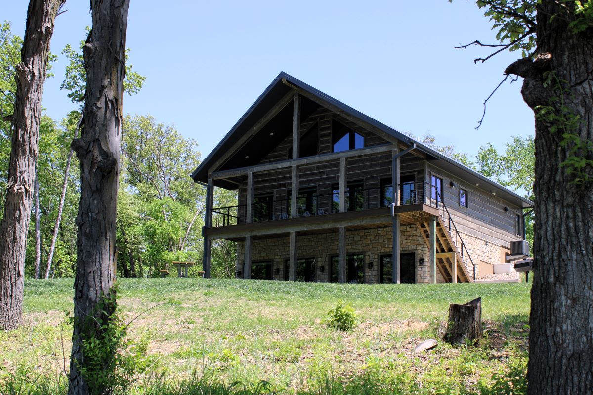 View from grass lawn and timber looking up to cabin deck and patios