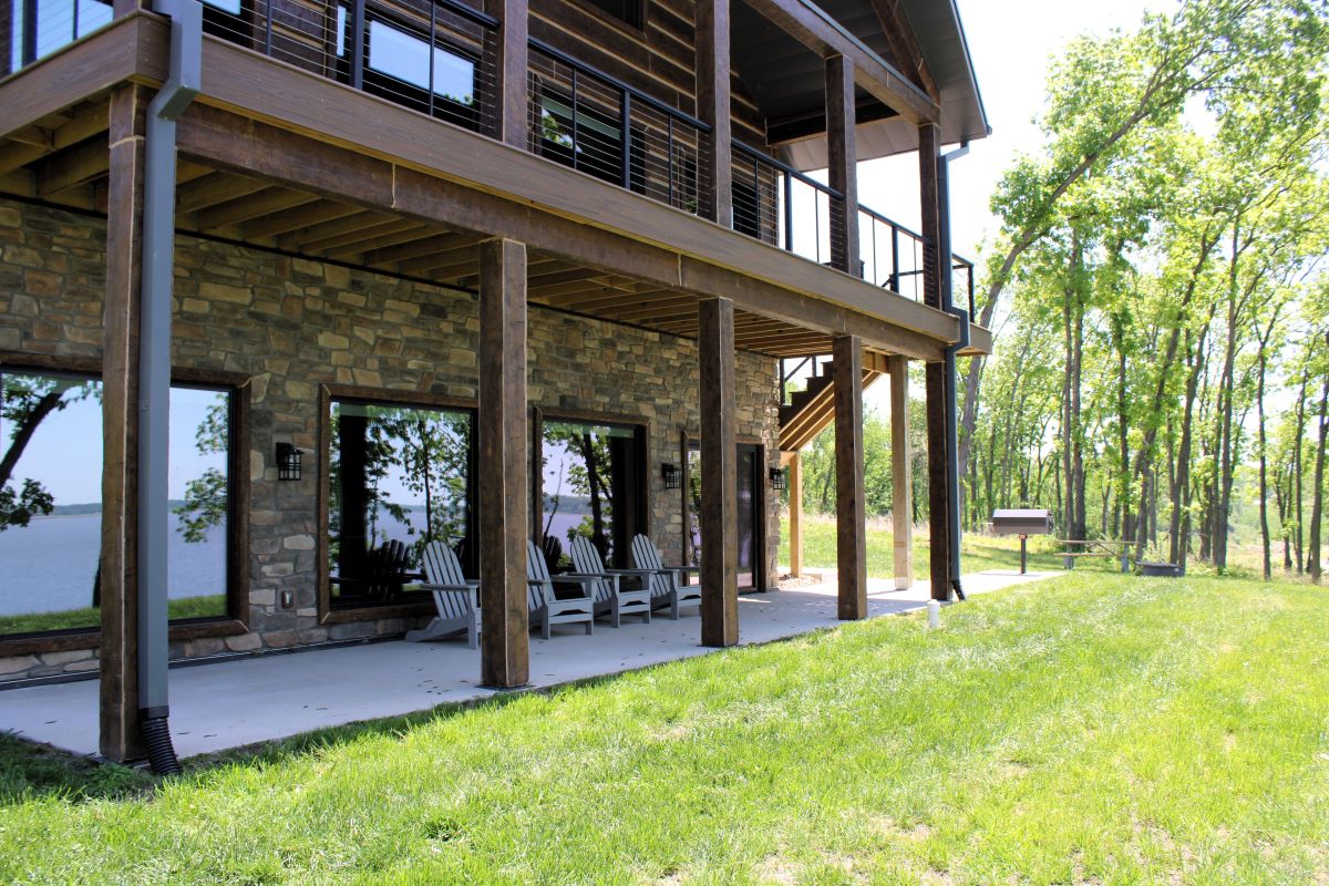 Upper level deck and lower level patio with chairs and picnic table on a modern style cabin, a grill