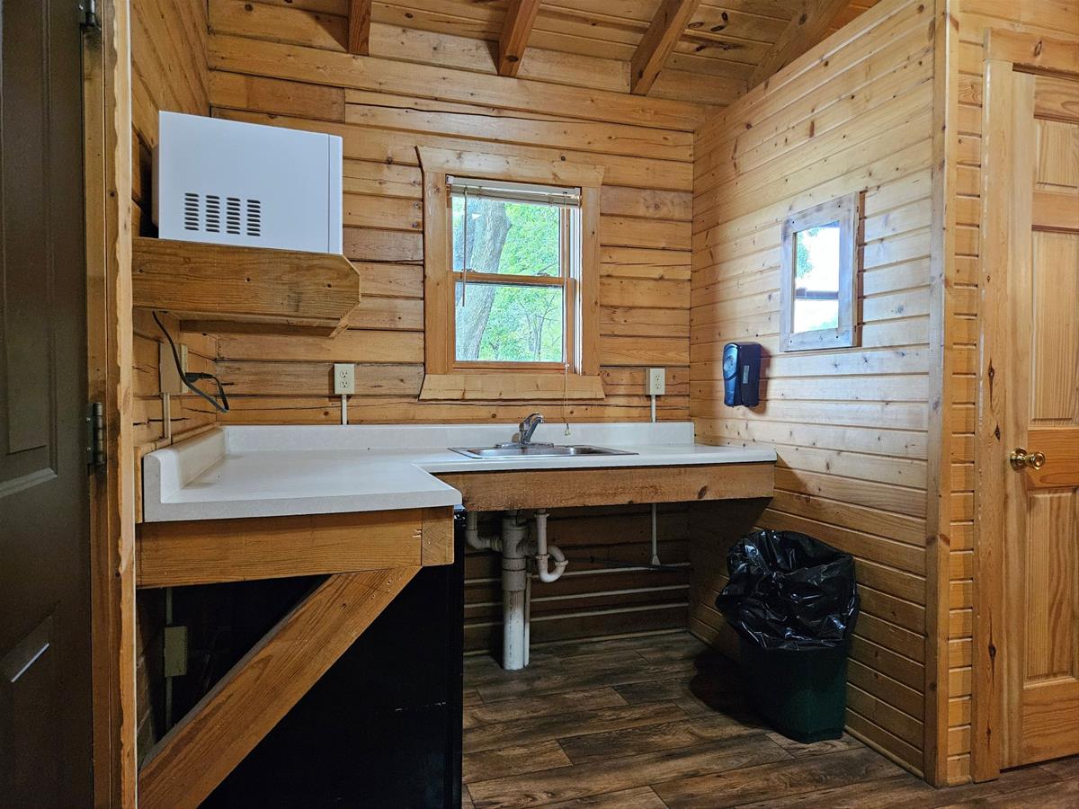 Bluestem - Cabin interior showing kitchen sink below a window and toilet room to the right.