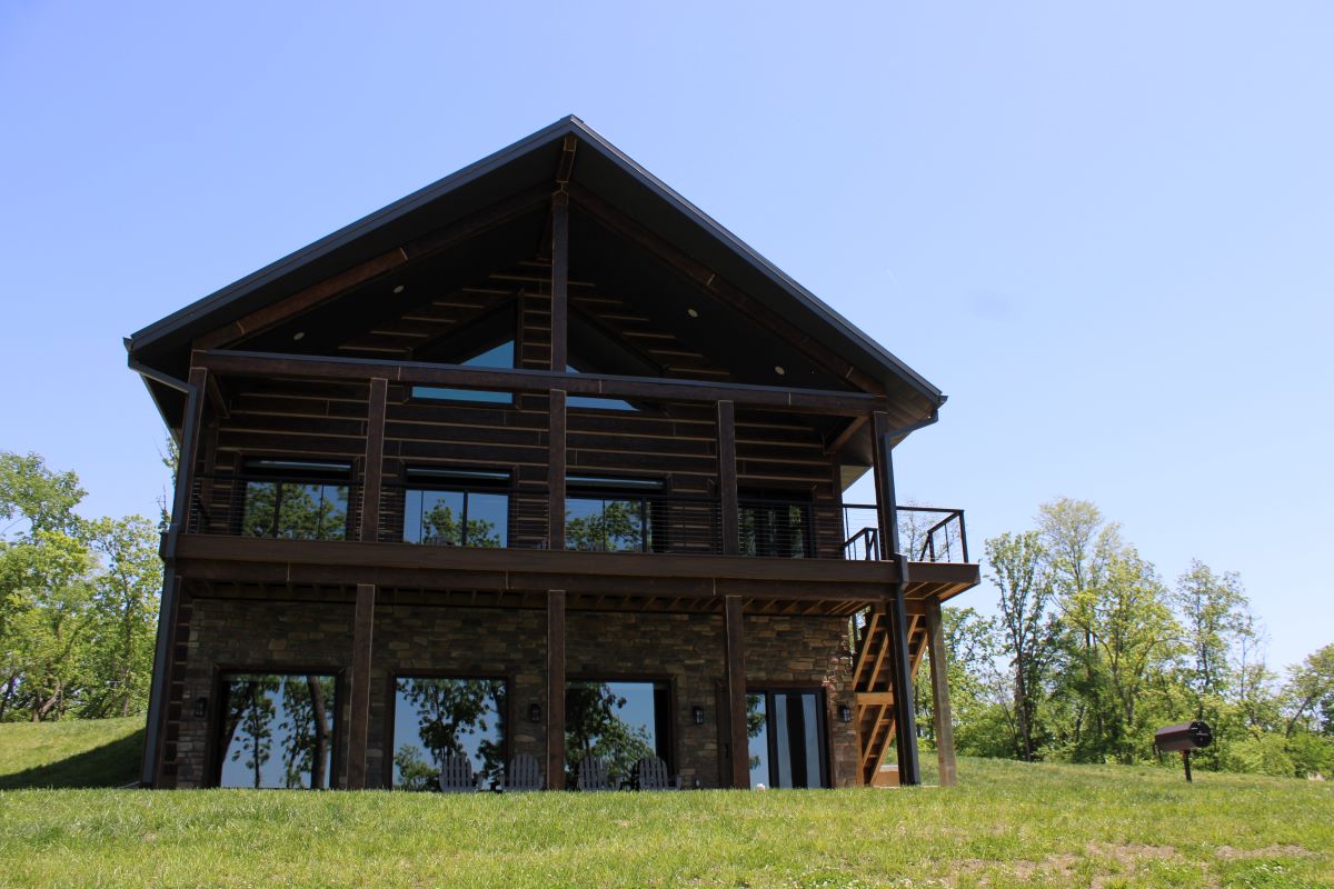 Grass lawn leading up to cabin with upper and lower deck 