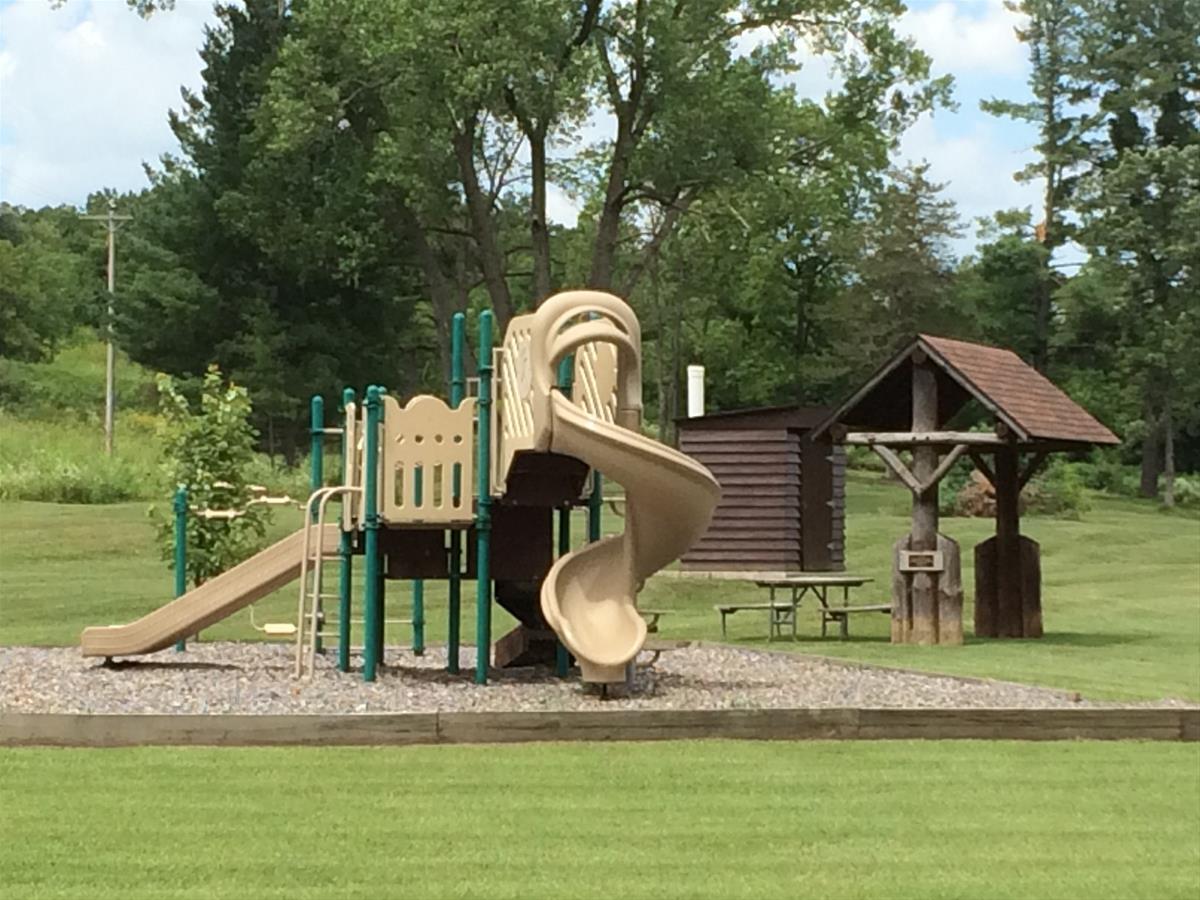 Playground with picnic kiosk and pit toilet in background