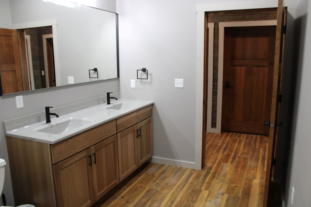 Modern bathroom with double sink vanity and large mirror, open door leading to hallway