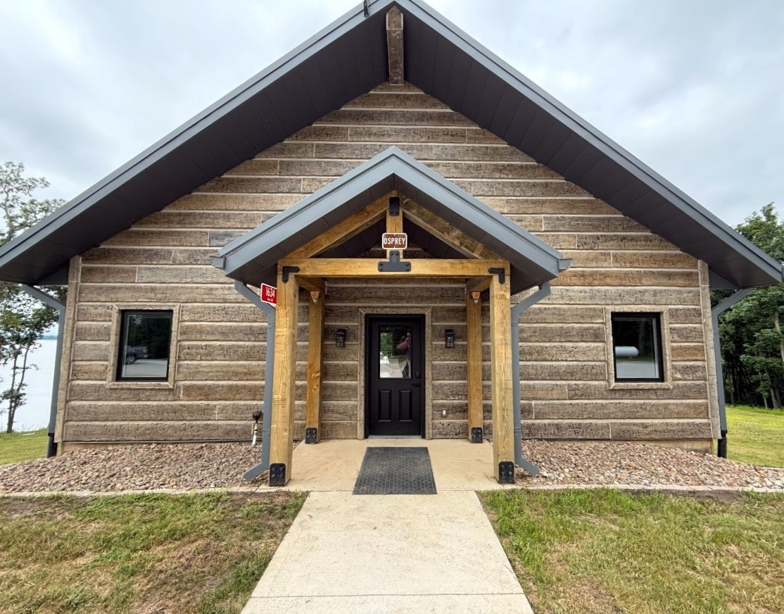 Front door entrance of a modern style cabin with lake and timber in the background