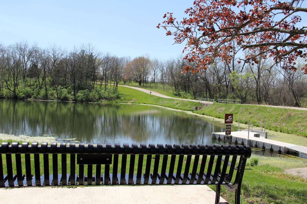 Park bench with pond and kayak dock in the background