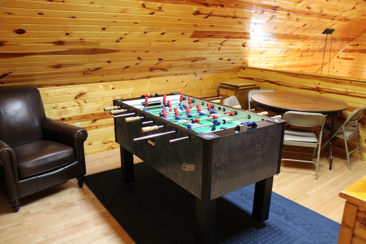 Game room with foosball table, table and 4 chairs, and board games in a side table on the upper floo