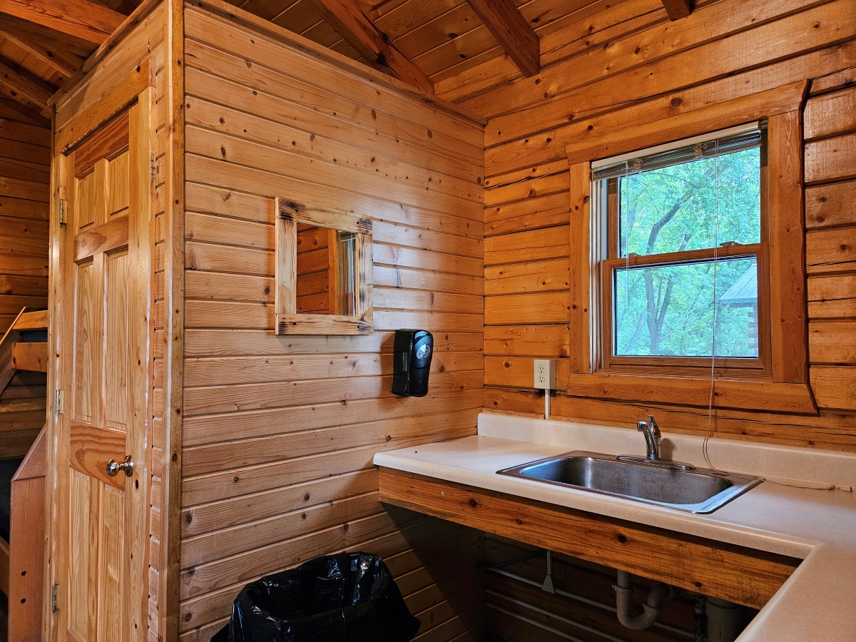 Prairie Rose - Cabin interior showing kitchen sink below a window and toilet room to the left 
