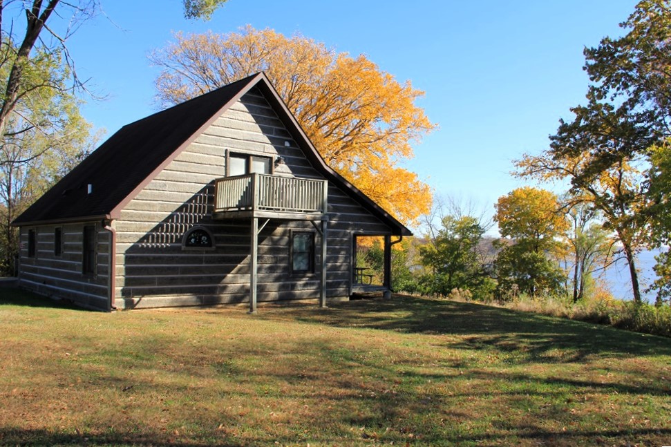 Log style cabin in woods with walk out porch from second story overlooking the lake in fall 