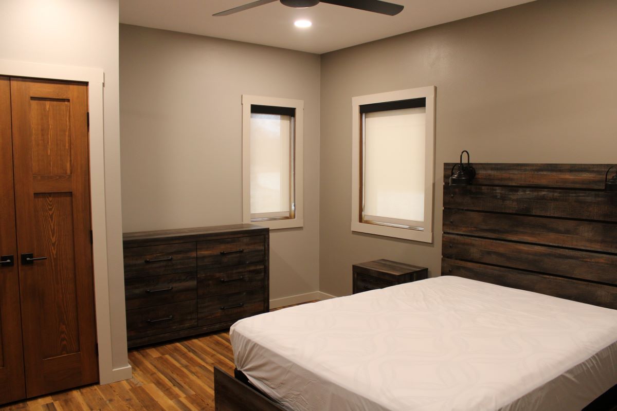 Queen bedroom on main level with ceiling fan, closet, dresser, and side tables
