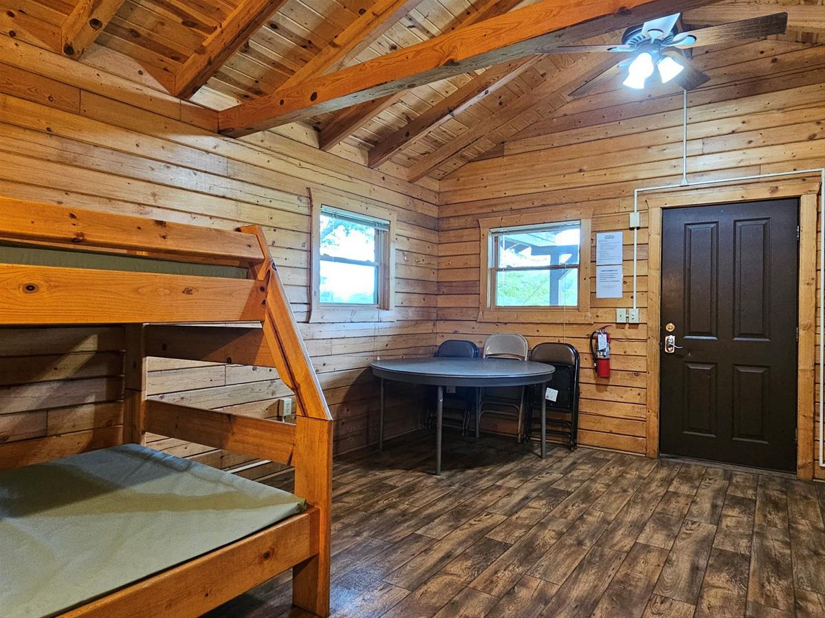 Bluestem - Cabin interior with wood siding, vinyl plank flooring, folding table & bunkbeds