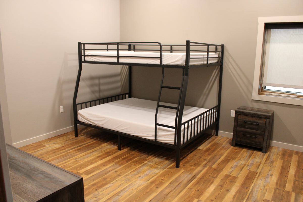 Bunk bed with full over queen mattresses, a side table. ceiling fan, and a window