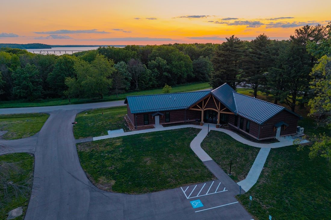 Log style office building with arched entryway, sunset and lake in the background over timber