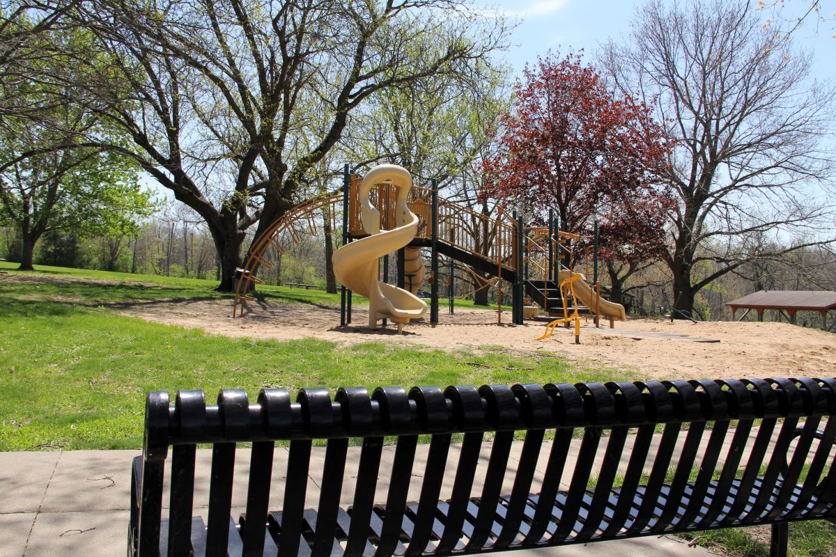 Park bench and playground equipment in the background in the spring