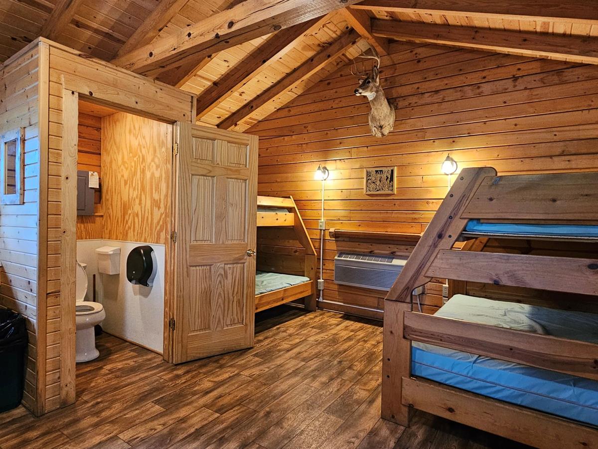 Whitetail - Cabin interior with two twin-over-full wooden bunk beds & enclosed private toilet.