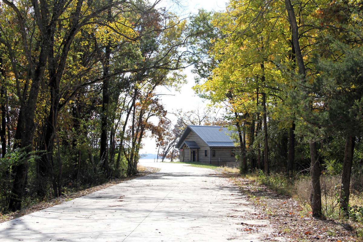 Paved driveway leading to modern style cabin in the timber with the lake in the background