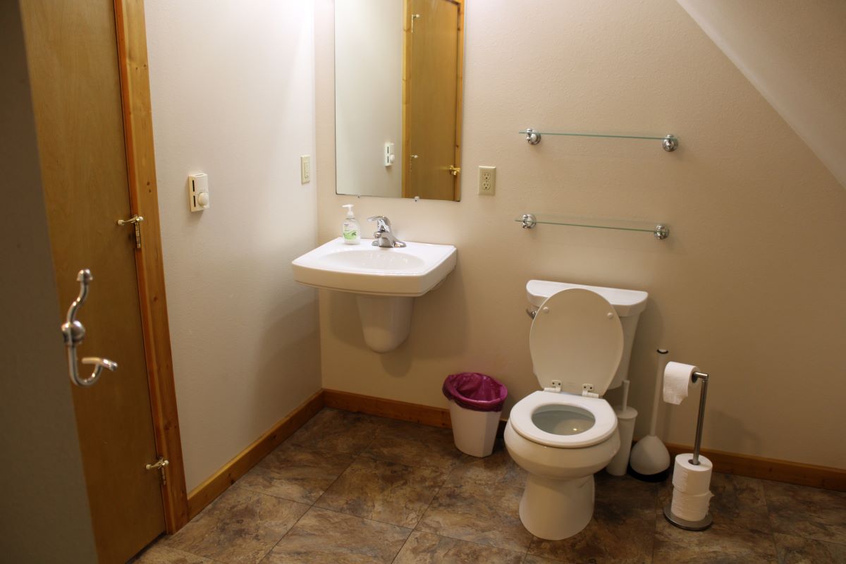 Bathroom in the upper level of cabin with toilet, sink, mirror, and small walk in shower