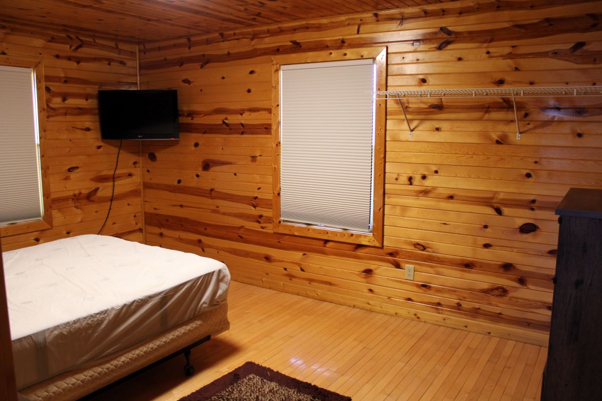 Queen bedroom with flat screen TV and side tables in a log style cabin 