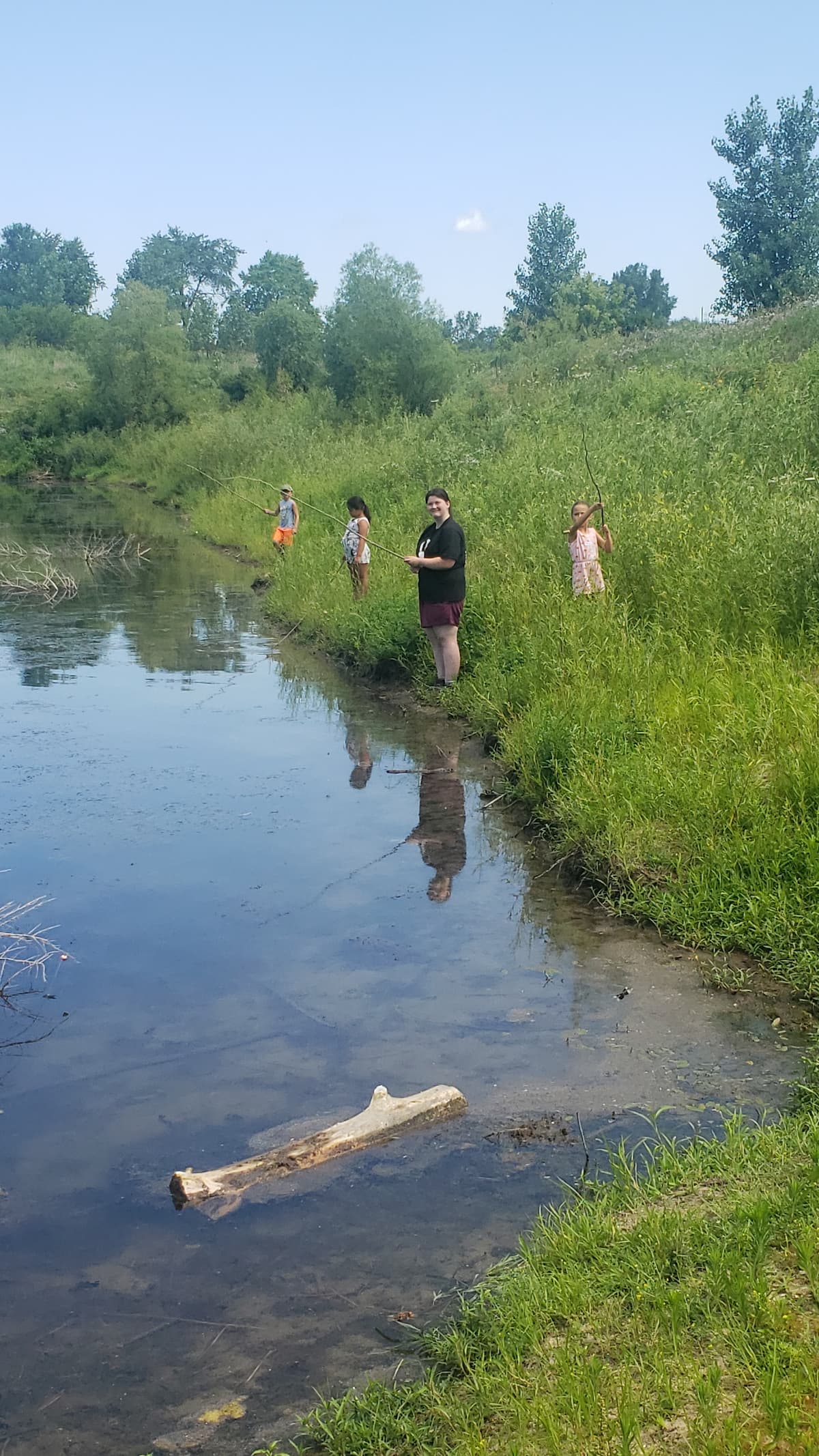 Kids fishing off the bank of the pond. 