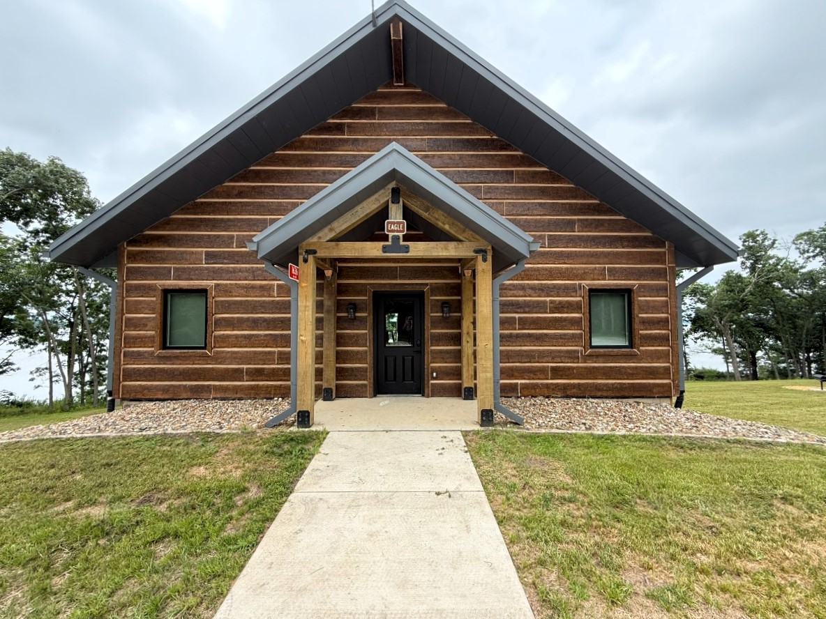 Front door entrance of a modern style cabin with lake and timber in the background