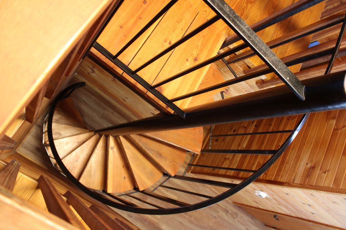 Winding wood staircase with metal hand railing that leads from second floor to main level 